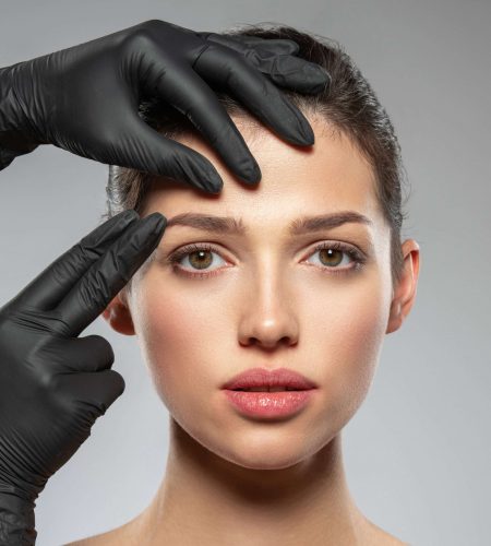 Face skin check before plastic surgery. Beautician touching woman face. Doctor checks a skin before plastic surgery. Beauty treatments. Plastic surgery doctor is touching face of a patient by hands