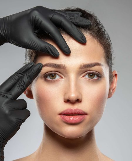 Face skin check before plastic surgery. Beautician touching woman face. Doctor checks a skin before plastic surgery. Beauty treatments. Plastic surgery doctor is touching face of a patient by hands