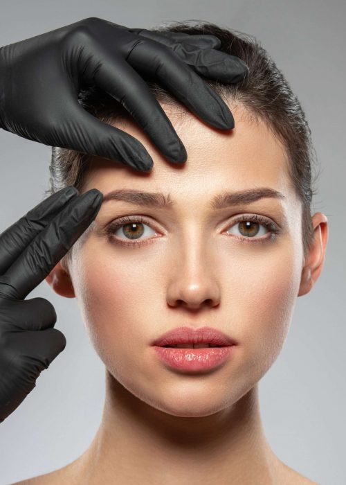 Face skin check before plastic surgery. Beautician touching woman face. Doctor checks a skin before plastic surgery. Beauty treatments. Plastic surgery doctor is touching face of a patient by hands